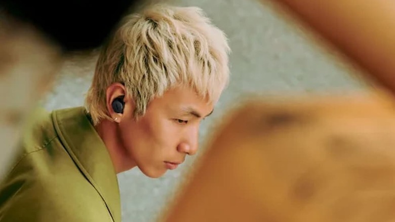 A person with blonde hair walking around with Bose QuietComfort Noise Cancelling Earbuds on.