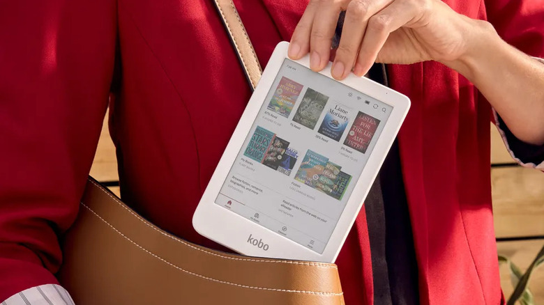 A white Kobo Clara Colour e-reader being placed by a person in a purse