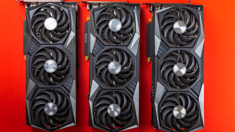 Three GPUs placed side by side on a red background
