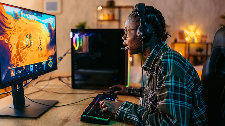 A person gaming on a keyboard and mouse, focusing on a monitor