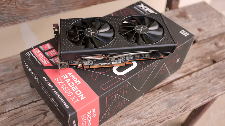 An AMD Radeon RX 6600 XT GPU on top of its box, placed on a wooden surface