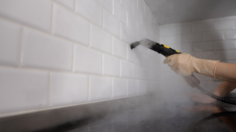 person using steam cleaner to clean kitchen grout