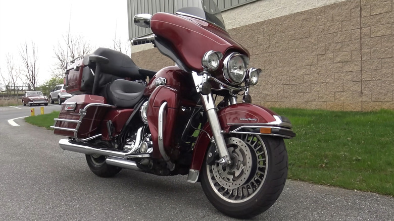 A gorgeous red Electra Glide FLHTCU motorbike parked at the side of a road next to a building