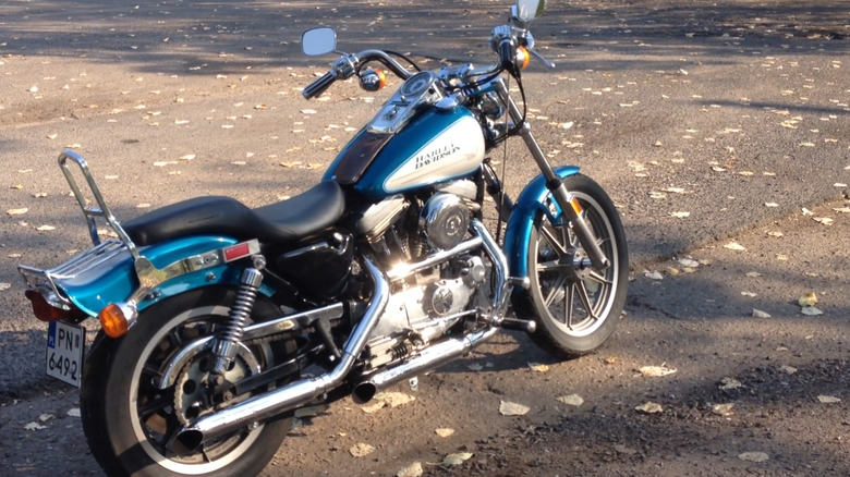 A beautiful silver and sky blue Harley-davidson Sportster 1200 with the evo engine from 1986 parked outside in the the shade