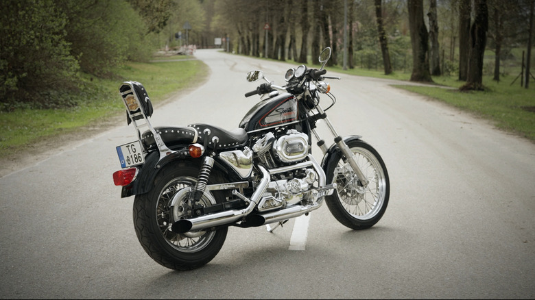 A silver and black Sportster 883 from 1986 parked diagonally in the middle of a remote road