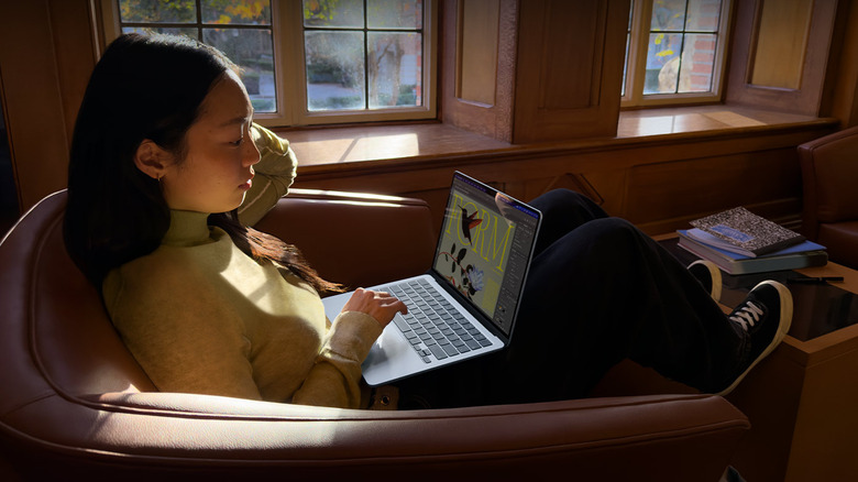 A woman sitting comfortably at home working on a MacBook Air.