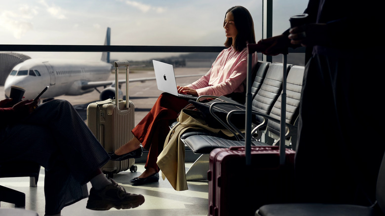 A woman working on her MacBook pro at the airport.