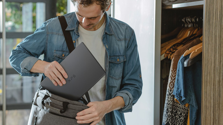 A man slipping the Dell XPS 14 into a shoulder bag.