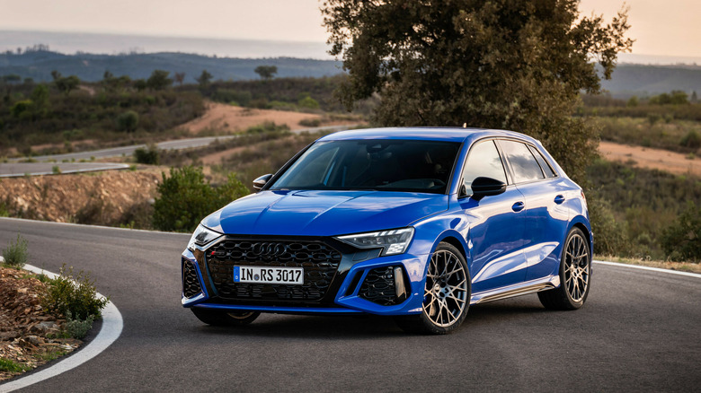 Blue 2024 Audi RS3 Sportback on an empty road front 3/4 view