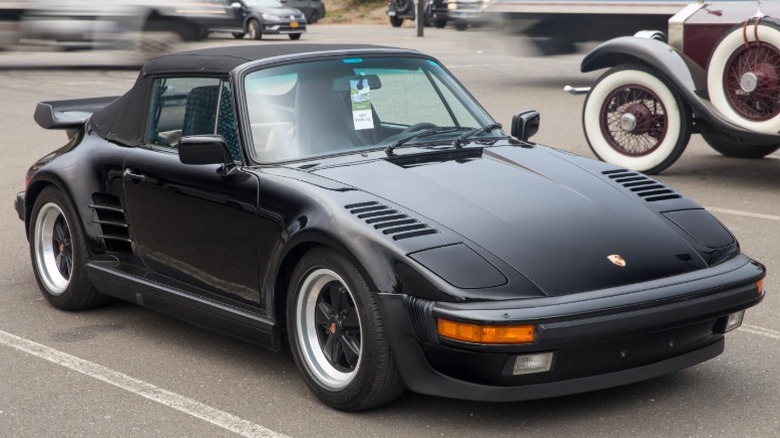 Black Porsche 911 Turbo Flatnose Cabriolet parked with vintage car in background