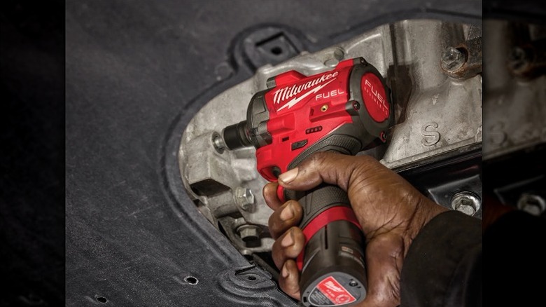 Using a Milwaukee impact wrench to fasten a fastener.