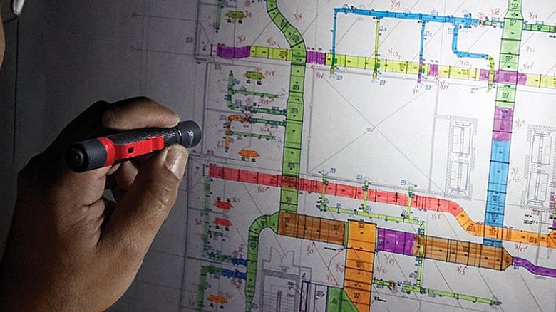 Using a pen light to view a blueprint map indicated with different colors.