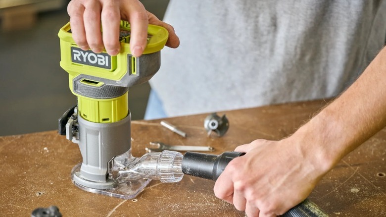 Person attaching a vacuum hose to the Ryobi 18V One+ Compact Router