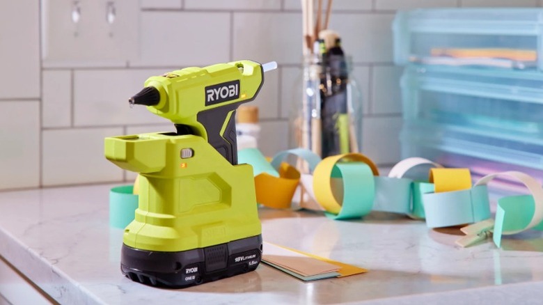 Ryobi 18V One+ Cordless Compact Glue Gun on a table with paper and crafting supplies in the background
