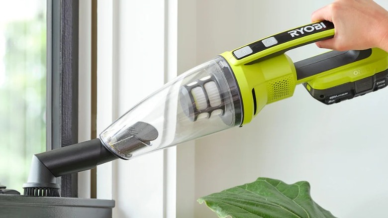 Person using a Ryobi 18V One+ Cordless Performance Handheld Vacuum to clean a windowsill
