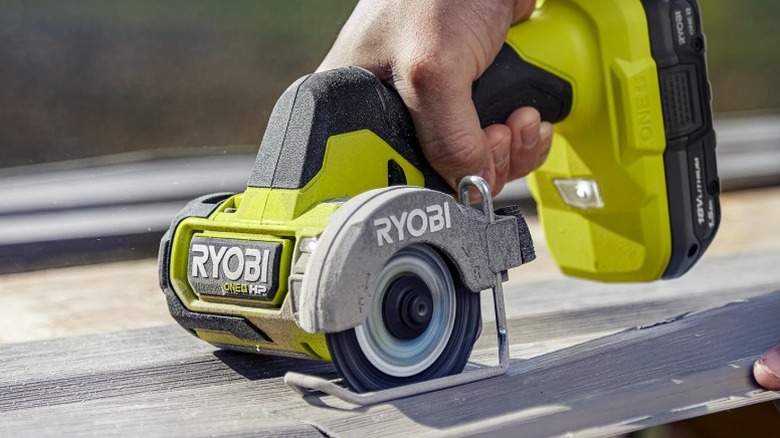 Person using a Ryobi 18V One+ HP Compact Brushless Cut-Off Tool to cut through plastic siding
