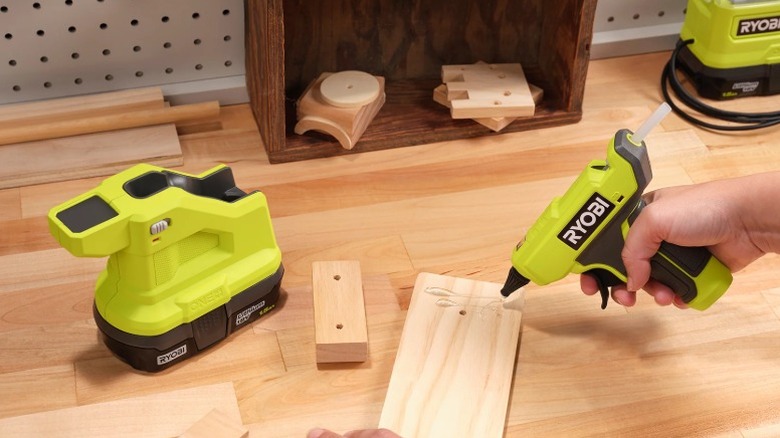 Person using a Ryobi 18V One+ Cordless Compact Glue Gun to apply hot glue to wood