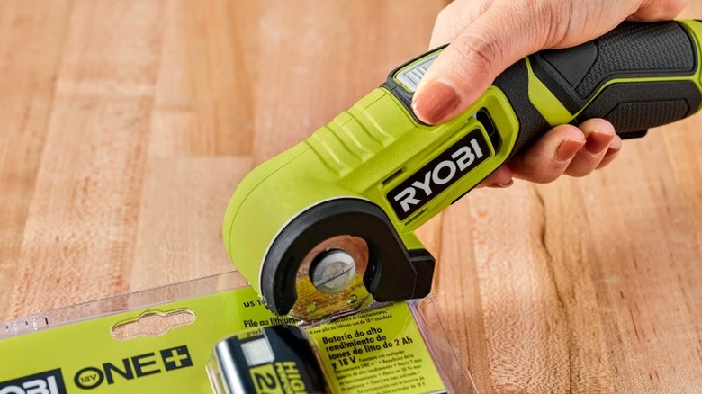 Person cutting through clamshell plastic packaging with a Ryobi USB Lithium Power Cutter