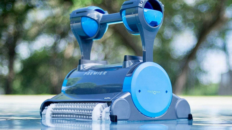 A Dolphin Premier pool robot with a top handle placed on water surface.
