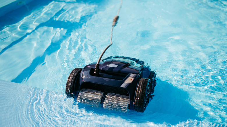 A pool robot connected to a cable entering a pool.