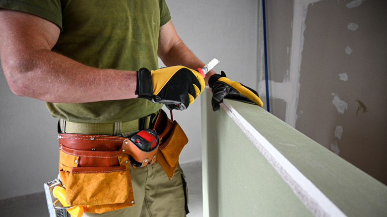 man holding utility knife over wood