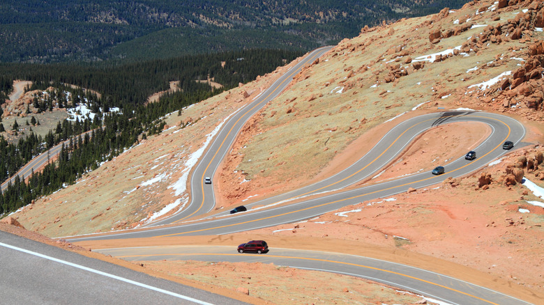 Sharp switchbacks along the Pikes Peak Highway in Colorado, winding through a rocky, snow-dusted alpine landscape.