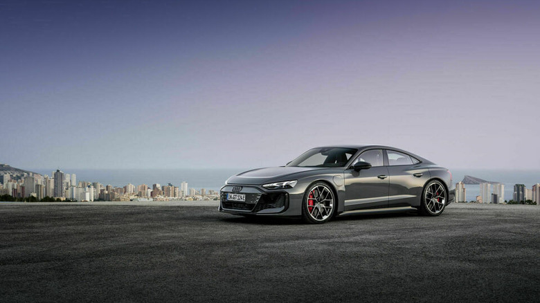 Gray Audi RS e-tron GT seen from left front with distant city and ocean in background