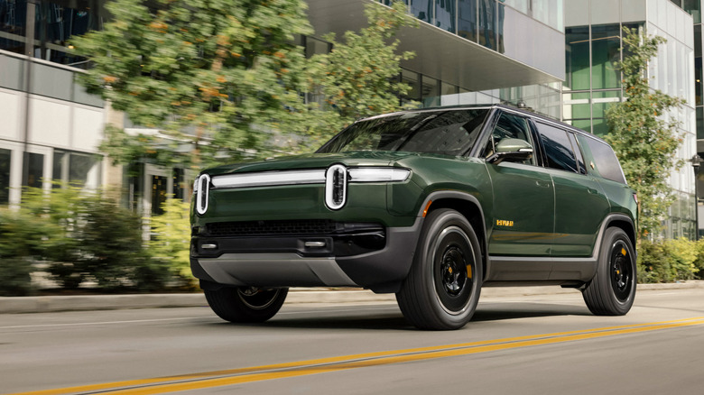 Green Rivian R1S SUV seen from left front on city street