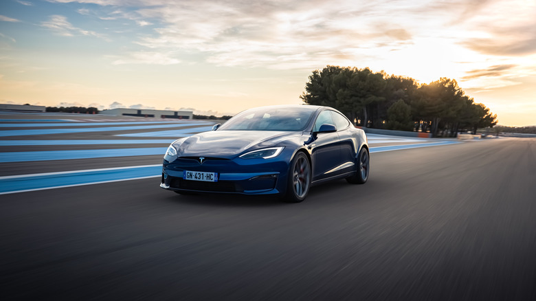 Blue Tesla Model S seen from left front on a track at twilight
