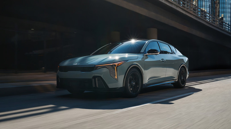 A green Kia K4 driving