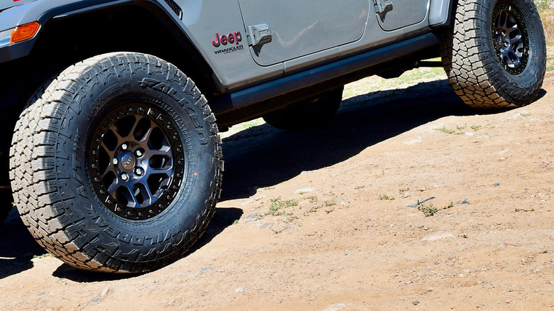 The Falken WildPeak A/T4W all-terrain tires on a dirt surface, attached to a jeep