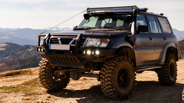 An off-road vehicle on a dirt surface overlooking hills and mountains