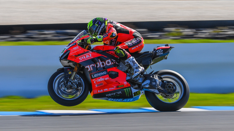 Motorcycle racer on Panigale V4R raising front wheel on racetrack