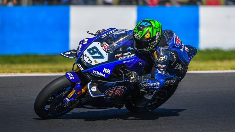 Yamaha R1 and rider leaning into turn on race course.