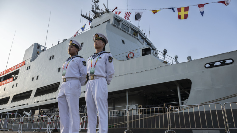 Chinese sailors standing in front of a warship