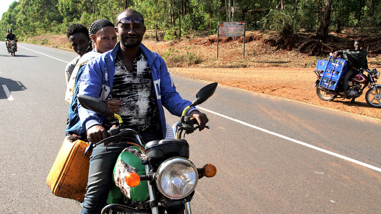 Three poeple share a motorbike on the Trans-African Highway.