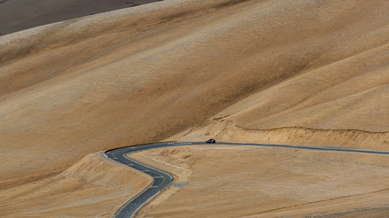 Car driving through barren landscape on National Highway 219.
