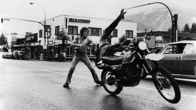 Sylvester Stallone pulling a man off a Yamaha XT250 motorcycle