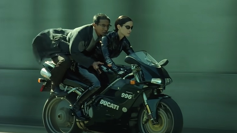 Trinity and man riding a Ducati 996