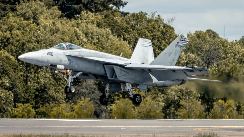 An gray F/A-18 Super Hornet flying slightly above the runway