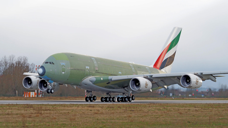 A green Airbus A380 MSN272 landing on the runway in Hamburg, Germany on a cloudy day.