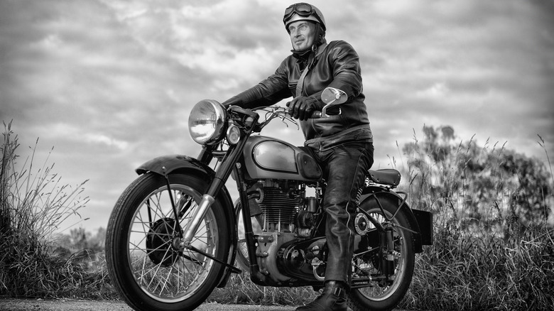 man in leather jacket and helmet with goggles on a motorcycle