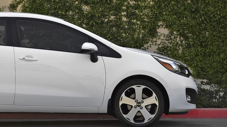 Front end of a white 2015 Kia Rio on pavement