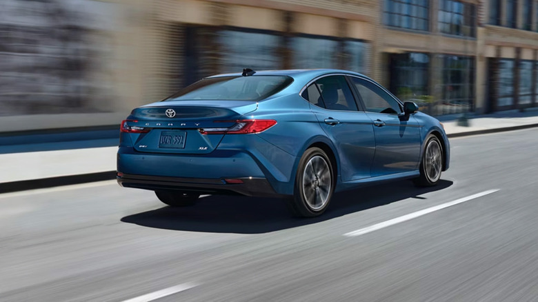 A blue Toyota Camry driving down a city street