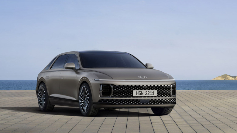 2026 Hyundai Azera luxury sedan parked on a tiled waterfront promenade, with a calm ocean and distant coastal city skyline in the background.