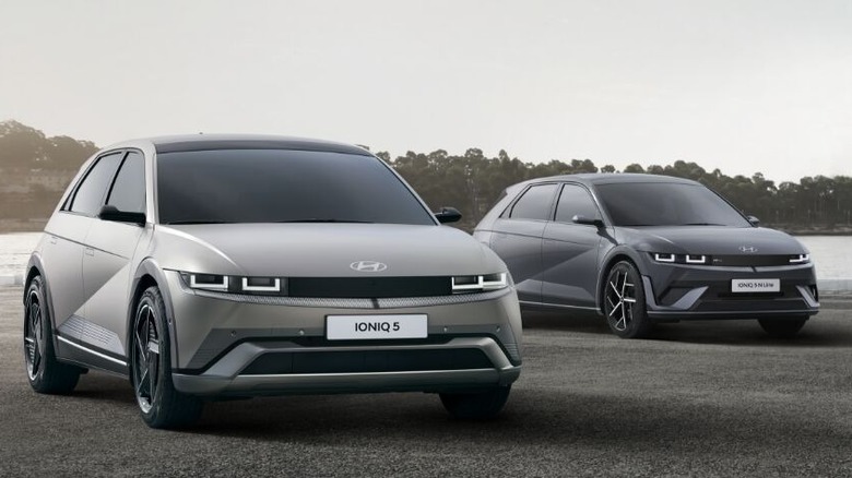 Two Hyundai IONIQ electric vehicles—IONIQ 5, IONIQ 5 N, —parked side by side on an open surface with a city skyline and water in the background.