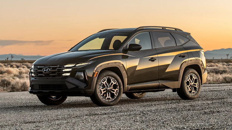2025 Hyundai Tucson SUV in a rugged desert landscape at sunset, showcasing its bold front grille, angular body lines, and off-road-inspired wheels.