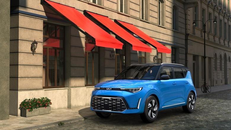 A Blue 2025 Kia Soul parked outside a shop, in the shade of a red awning