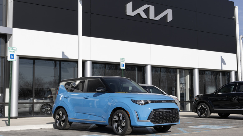 A blue Kia Soul standing outside a KIA showroom
