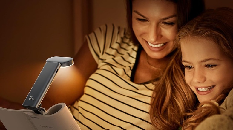 Woman and child reading a book with a light shining on the pages